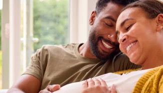 Egg donor recipients smiling at the mom's pregnant belly.