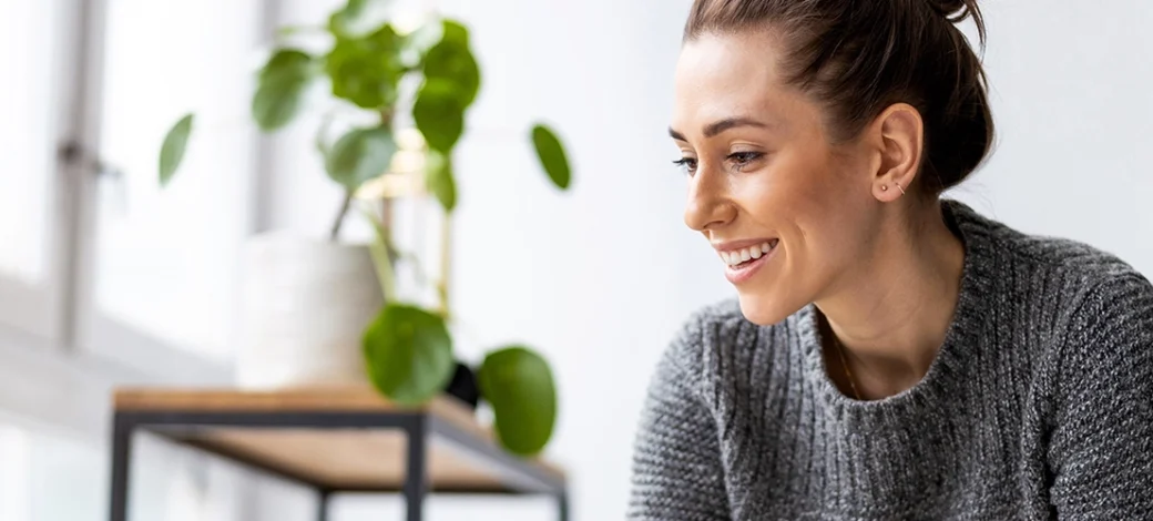 Woman smiling at laptop as she finds her perfect donor egg.