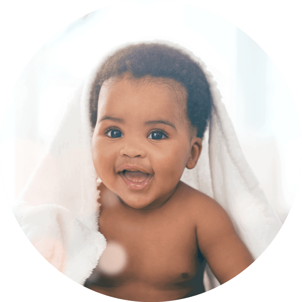 A baby smiles warmly under a soft blanket.
