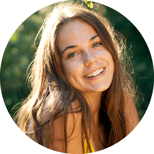 An egg donor with a yellow tank top and long blonde hair smiles outside.