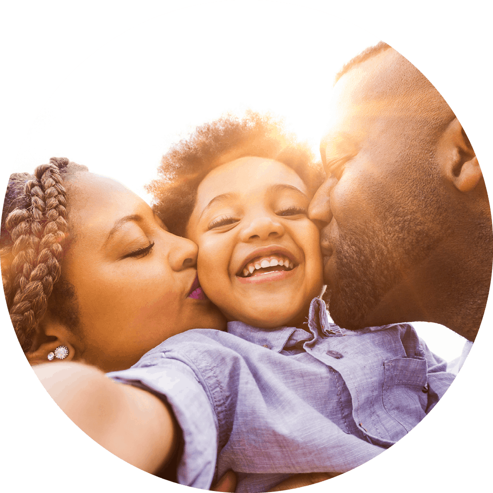 A family shares a tender moment as a mother and father kiss their child's cheek, showing love and affection.