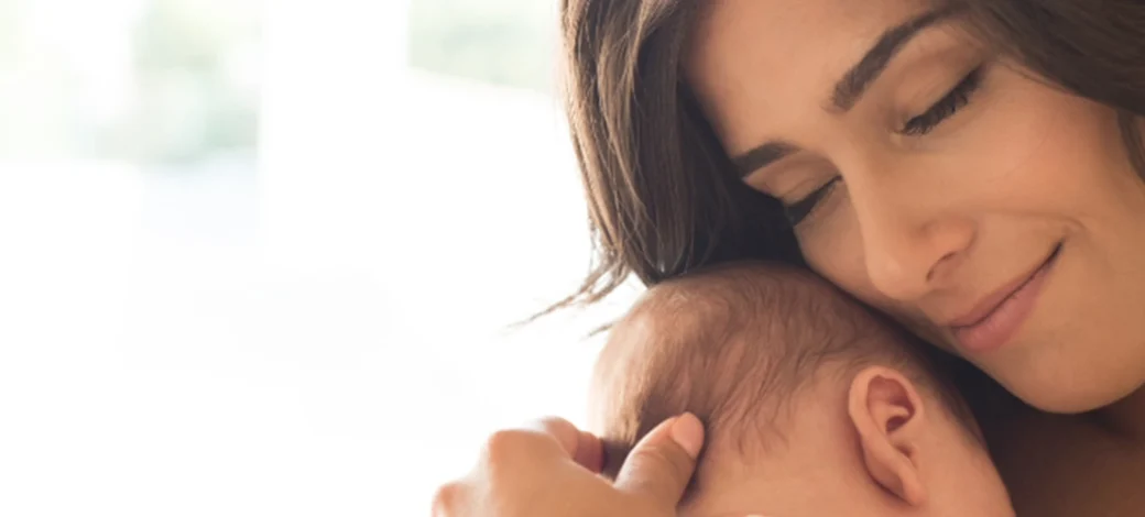 New mother holding her donor egg conceived baby, happy she chose frozen donor eggs.