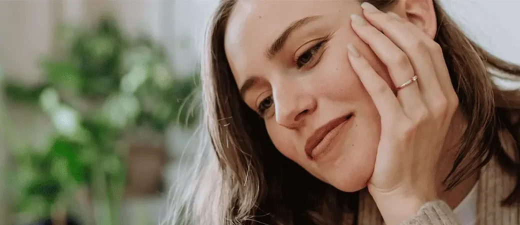 A woman laying on her bed looking at her phone wondering if she should be a non-ID or ID-option egg donor.