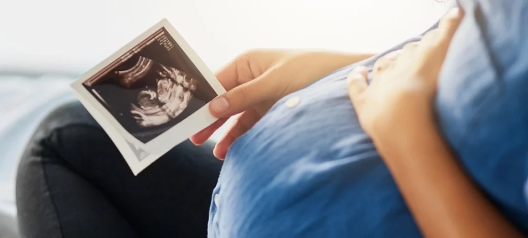 Pregnant woman looking at her sonogram of her donor egg conceived baby.
