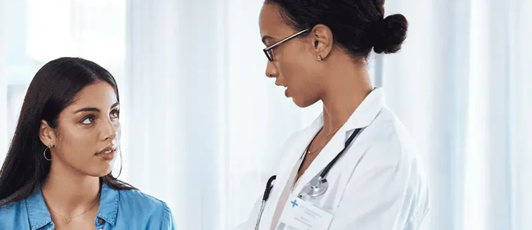 A woman and her doctor are discussing the BMI requirements for egg donation in a medical setting.