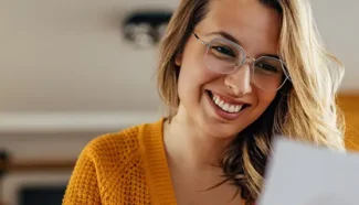 A woman in a yellow shirt looking at a document containing tips for egg donors looking to complete their egg donor cycle.