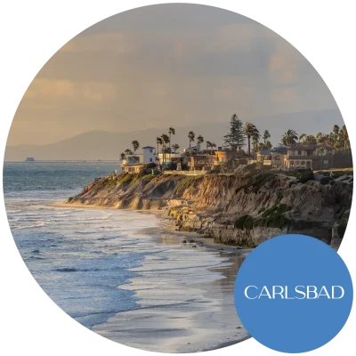 Aerial view of Carlsbad, CA, showcasing the city's buildings on the beachfront with incoming waves. Become an egg donor today!